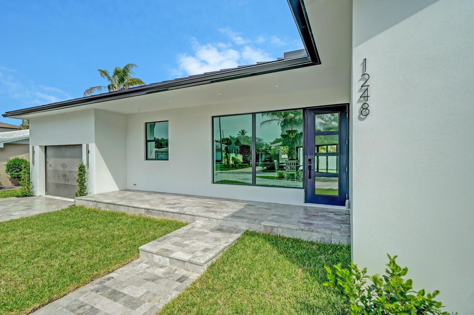A modern white house exterior features a tiled walkway, a dark front door, and large windows — 1248 N Harbor Drive, Singer Island FL 33404, SINGER ISLAND, FL