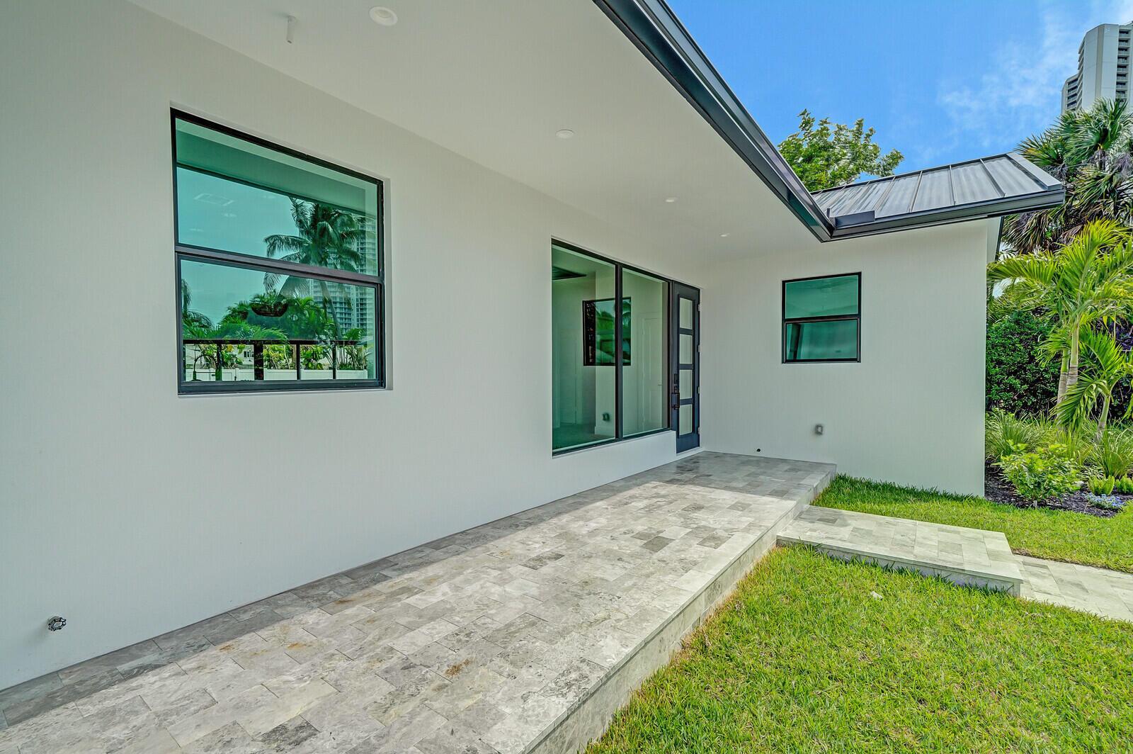 A modern white house exterior features a stone patio, large windows, and a metal roof — 1248 N Harbor Drive, Singer Island FL 33404, SINGER ISLAND, FL