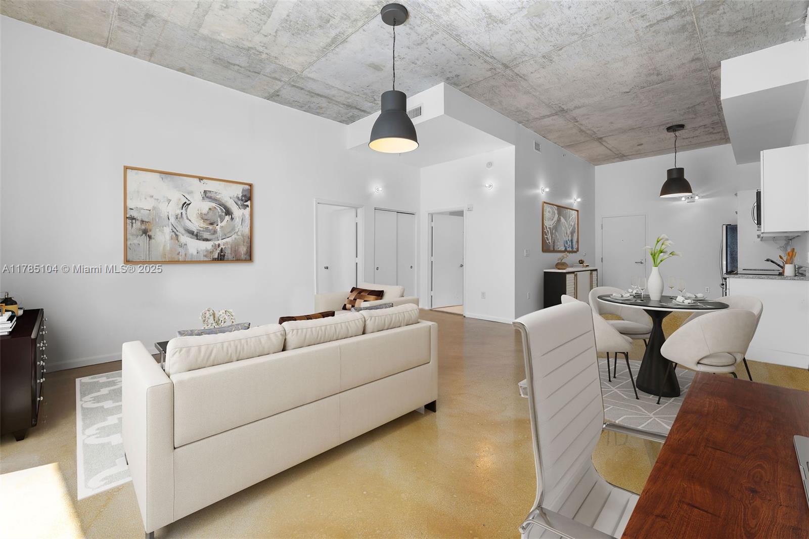 This open-concept living and dining area features a concrete ceiling and polished concrete floors — 2001 Meridian Ave # 412, Miami Beach FL 33139, MIAMI BEACH, FL
