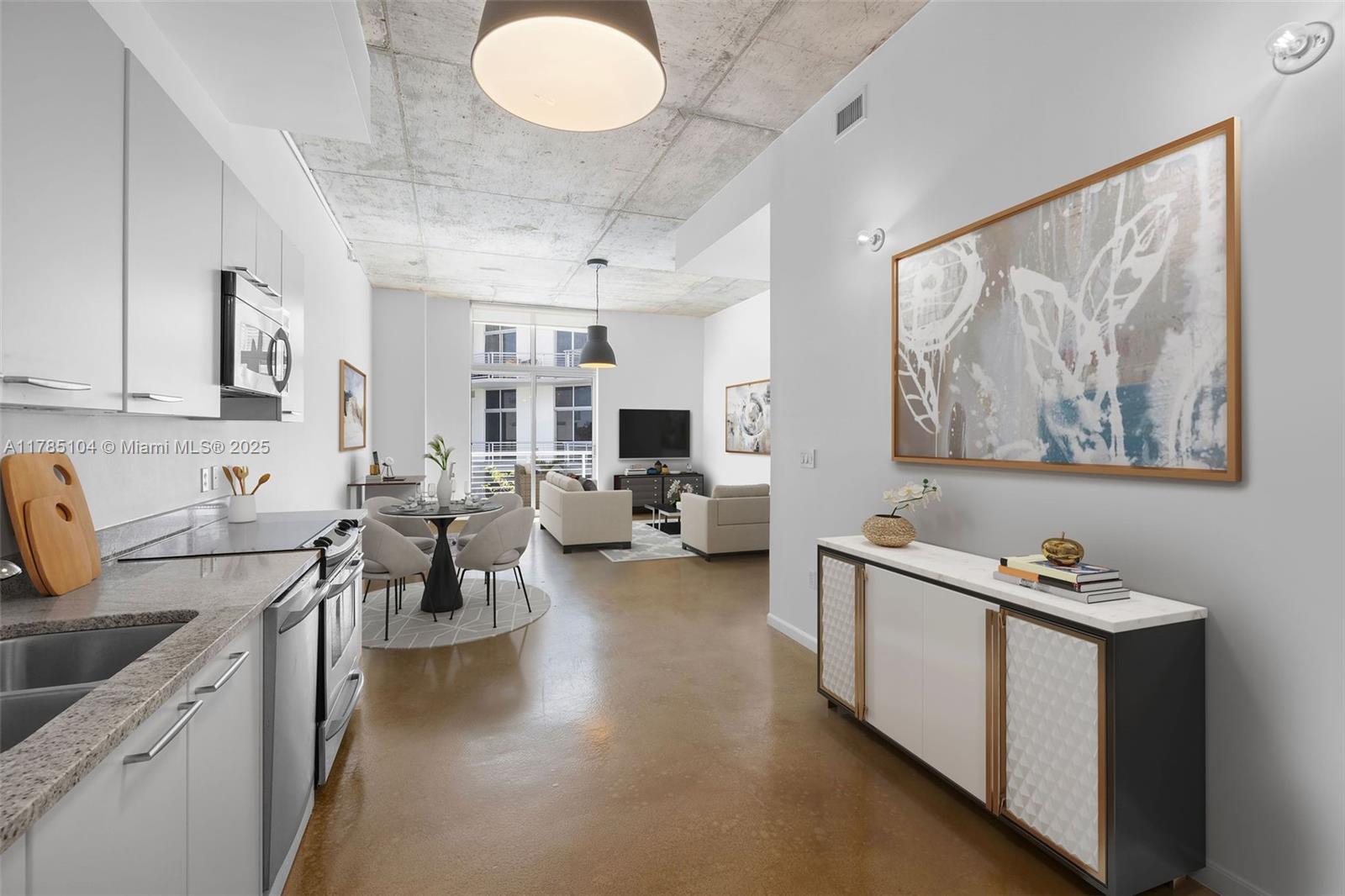 An open-concept kitchen and living area features concrete ceilings, polished floors, and modern furnishings — 2001 Meridian Ave # 412, Miami Beach FL 33139, MIAMI BEACH, FL