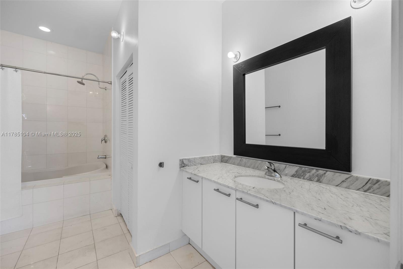 A bathroom features a white vanity with a marble countertop, a mirror, and a tub-shower — 2001 Meridian Ave # 412, Miami Beach FL 33139, MIAMI BEACH, FL
