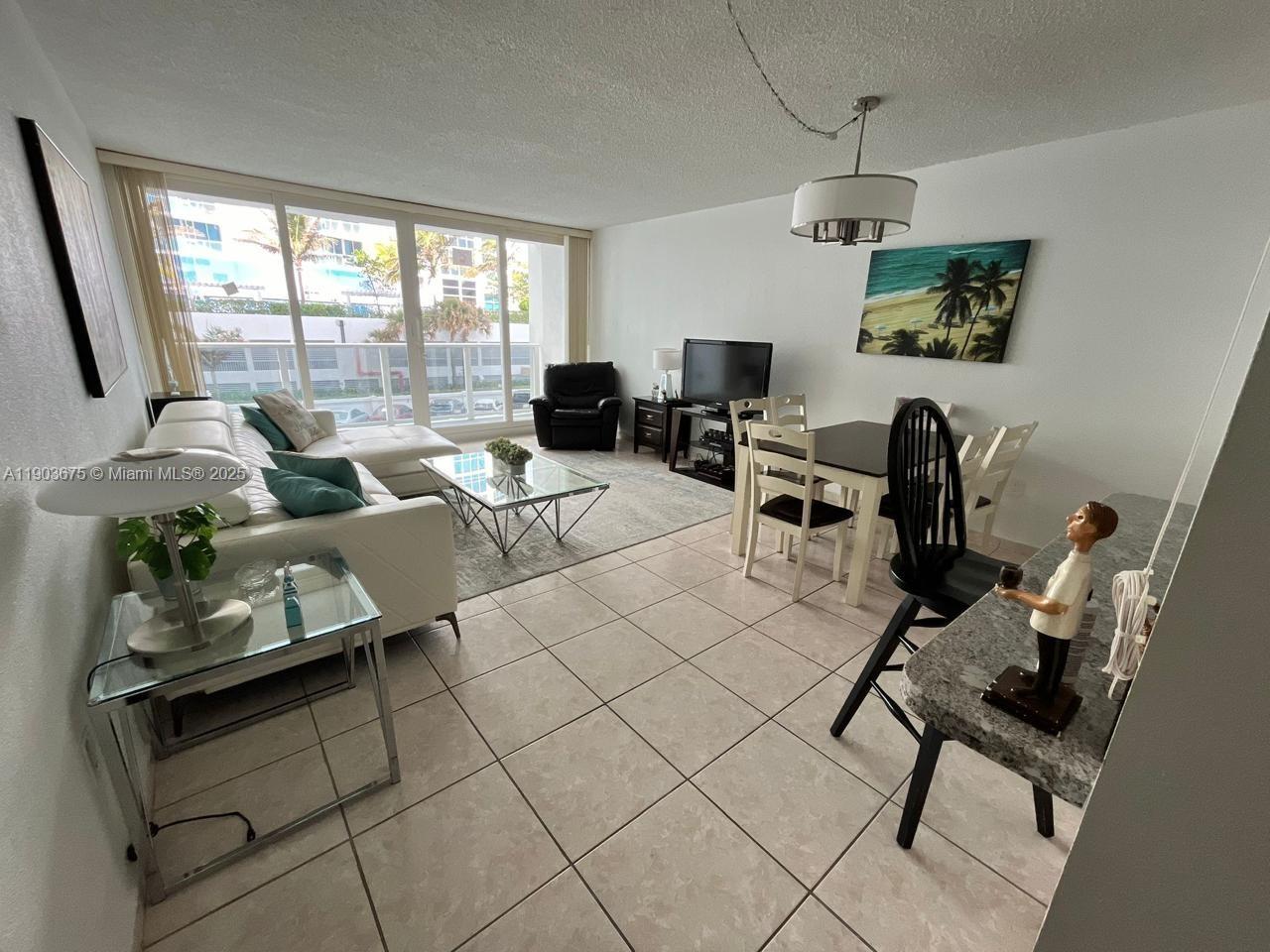 A living and dining area features white tile floors, a sectional sofa, and floor-to-ceiling windows — 3505 S Ocean Dr # 208, Hollywood FL 33019, HOLLYWOOD, FL