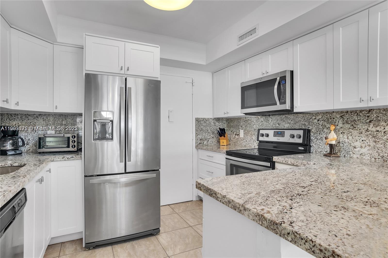 A kitchen features white cabinets, granite countertops, and stainless steel appliances — 3505 S Ocean Dr # 208, Hollywood FL 33019, HOLLYWOOD, FL