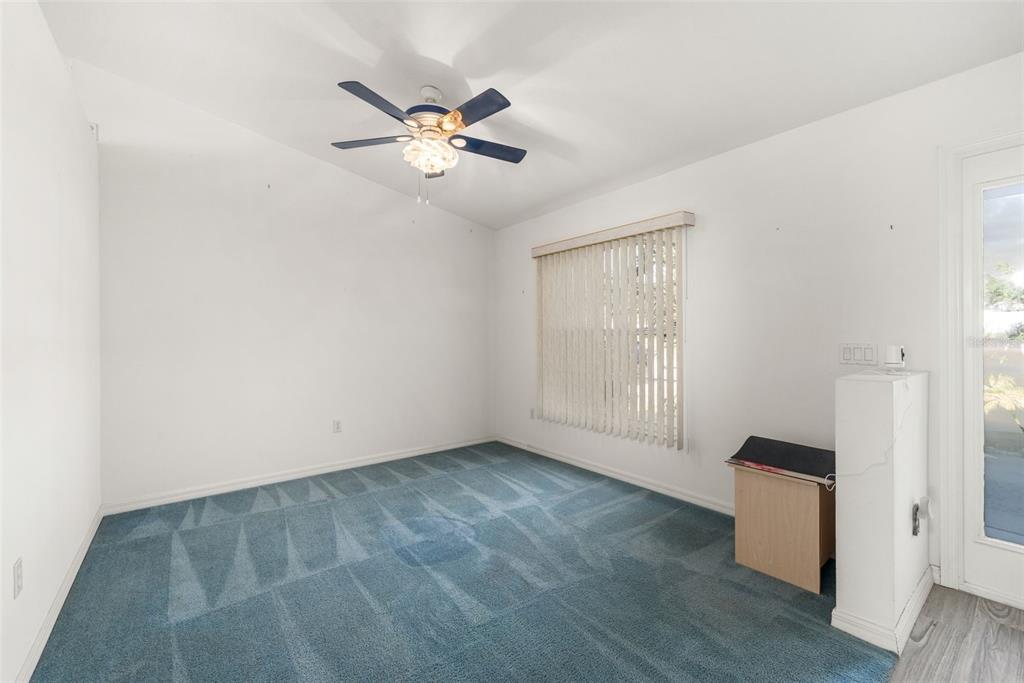 An empty room with blue carpet, white walls, a ceiling fan, and a glass door — 49 BAHIA TRACE COURSE, OCALA, FL