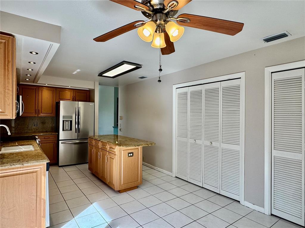 A kitchen features wood cabinets, granite countertops, stainless steel appliances, and white tile flooring — 4720 PERIDIA BOULEVARD E, BRADENTON, FL