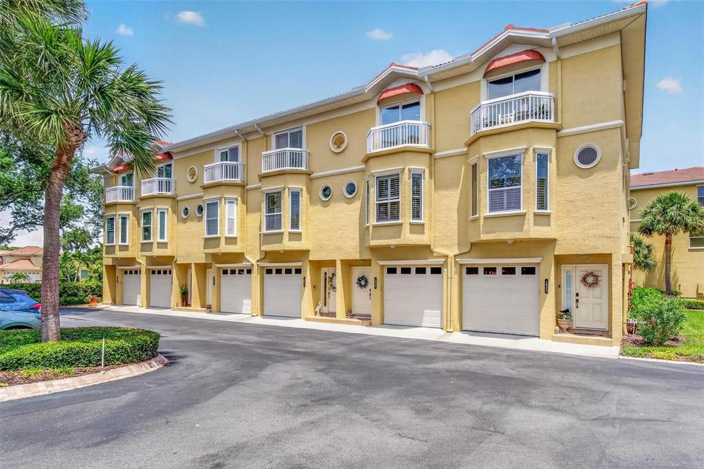A multi-story yellow townhouse complex features multiple garage doors, balconies, and a paved driveway — 1033 PINELLAS BAYWAY  S, TIERRA VERDE, FL