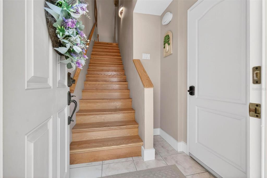A wooden staircase leads upward from a tiled entryway between two white doors — 1033 PINELLAS BAYWAY  S, TIERRA VERDE, FL