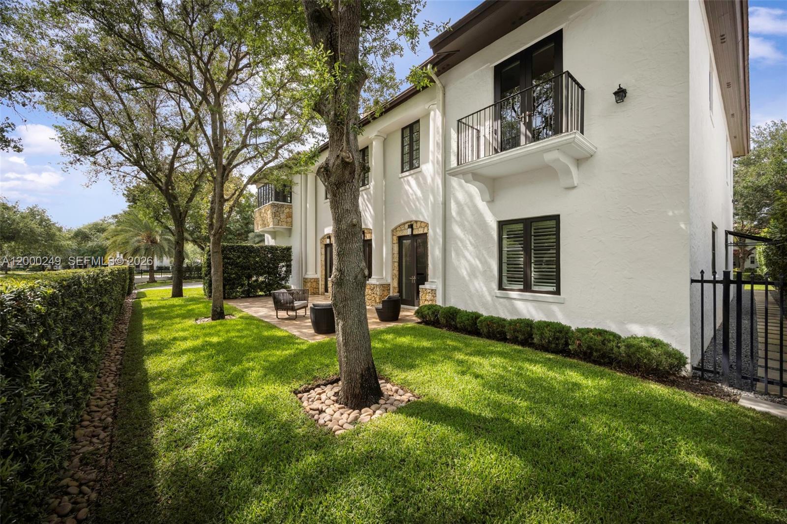 A white two-story house features a balcony, stone accents, and a landscaped backyard — 475 Amalfi Ave, Coral Gables FL 33146, CORAL GABLES, FL
