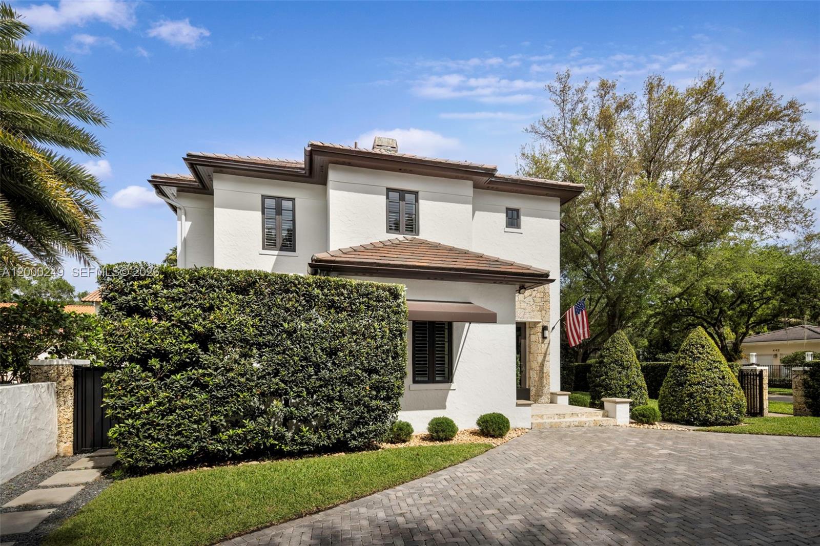 A two-story white stucco house features a tiled roof, stone accents, and a paved driveway — 475 Amalfi Ave, Coral Gables FL 33146, CORAL GABLES, FL