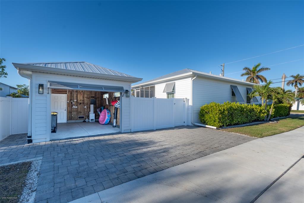 A white detached garage and house exterior with a paved driveway and white privacy fence — 327 HARVEY STREET, PUNTA GORDA, FL