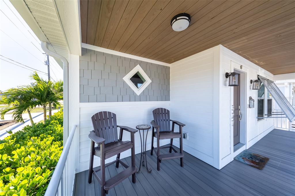 A covered porch features two dark chairs, a small table, and gray shingle siding — 327 HARVEY STREET, PUNTA GORDA, FL