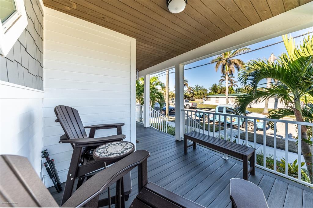 A covered front porch features dark composite decking, white railings, and outdoor seating — 327 HARVEY STREET, PUNTA GORDA, FL
