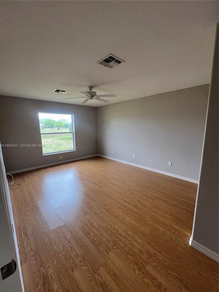 An empty bedroom features light gray walls, wood-look flooring, a ceiling fan, and one window — 1679 SW 156th Ln, Ocala FL 34473, OCALA, FL