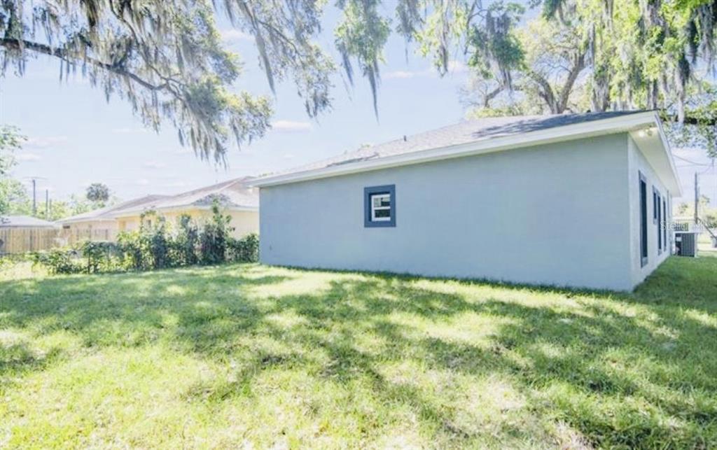 The exterior side view of a light blue house features a small window and lawn — 617 HOLMES AVENUE, DAYTONA BEACH, FL