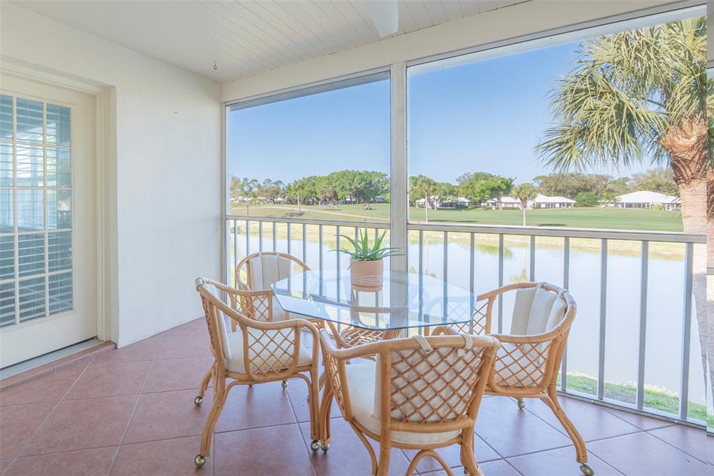A screened-in patio with tile flooring, wicker furniture, and a view of a golf course — 425 CERROMAR TERRACE UNIT 459, VENICE, FL
