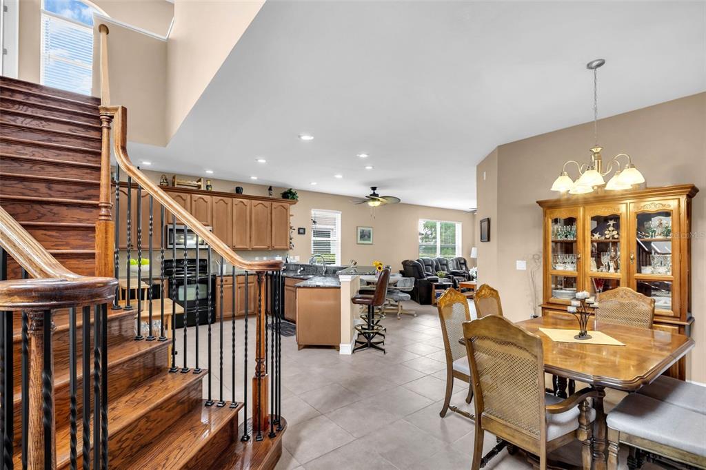 A view from a staircase looking into an open-concept kitchen, dining area, and living room — 1460 RIBOLLA DRIVE, PALM HARBOR, FL