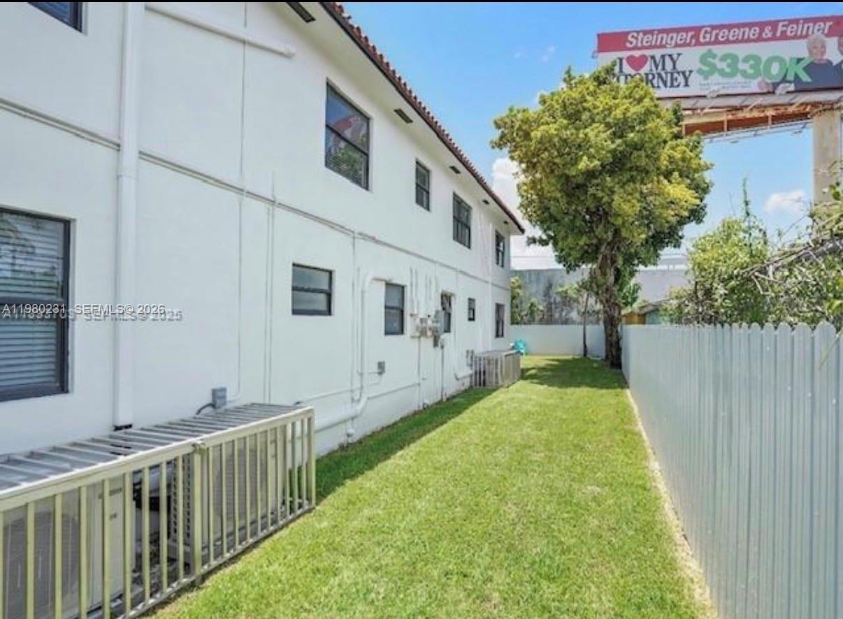 A narrow grassy side yard runs along the exterior wall of a white two-story building — 584 NW 30th St, Miami FL 33127, MIAMI, FL