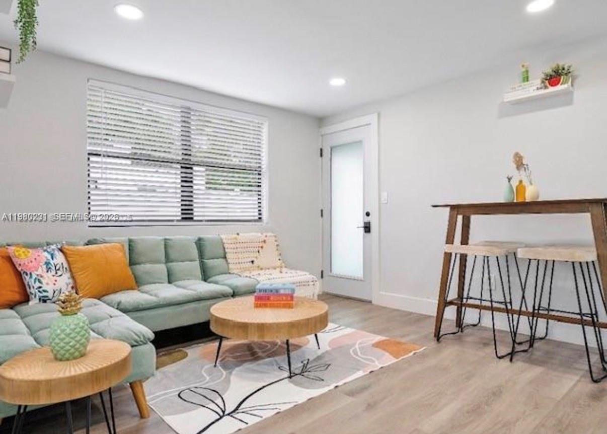 A living room features a light green sectional sofa, a round coffee table, and a bar-height table — 584 NW 30th St, Miami FL 33127, MIAMI, FL