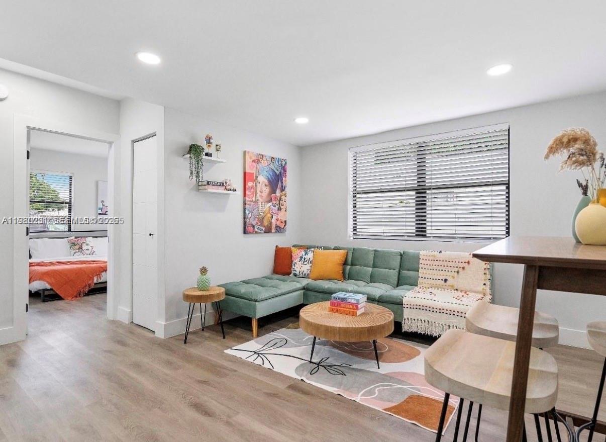 A living room features a green sectional sofa, a round coffee table, and wood flooring — 584 NW 30th St, Miami FL 33127, MIAMI, FL