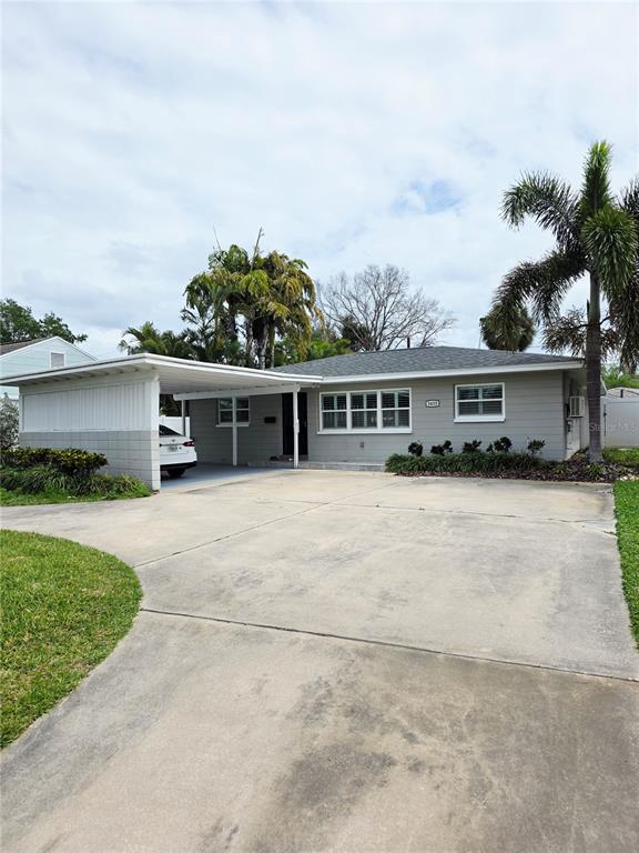 A single-story house with gray siding, a large concrete driveway, and an attached carport — 3435 OVERLOOK DRIVE NE, ST PETERSBURG, FL