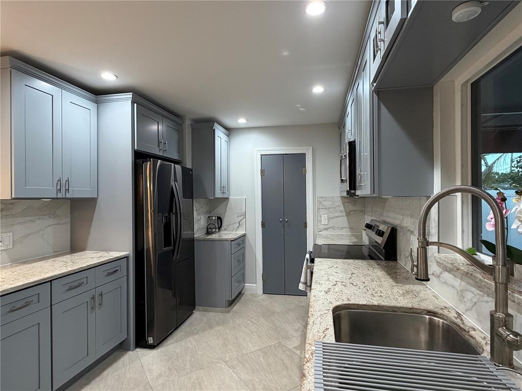 A kitchen features gray shaker cabinets, granite countertops, stainless steel appliances, and tile flooring — 3435 OVERLOOK DRIVE NE, ST PETERSBURG, FL