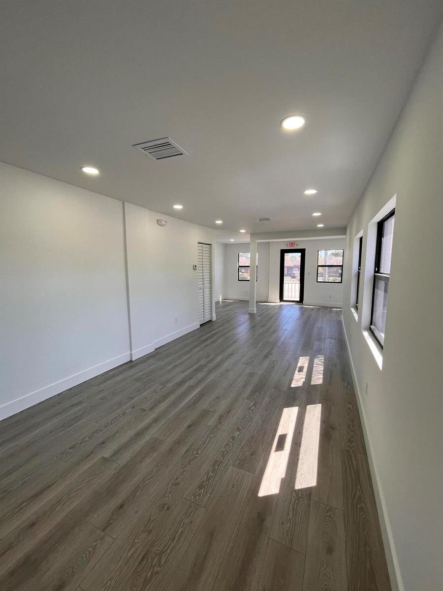 An empty room with light wood-look flooring, recessed lighting, and a glass exit door — 900 Federal Highway, Riviera Beach FL 33403, RIVIERA BEACH, FL