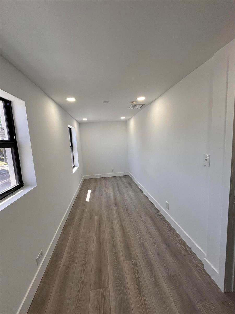 A narrow, empty room with white walls, recessed lighting, and light wood-look flooring — 900 Federal Highway, Riviera Beach FL 33403, RIVIERA BEACH, FL