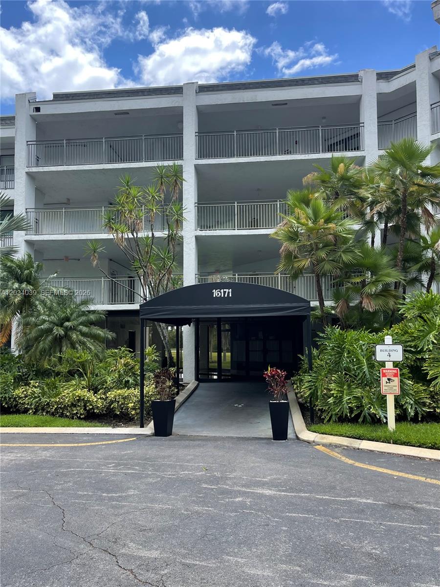 A three-story apartment building features a black entrance awning and lush tropical landscaping — 16171 Blatt Blvd # 212, Weston FL 33326, WESTON, FL