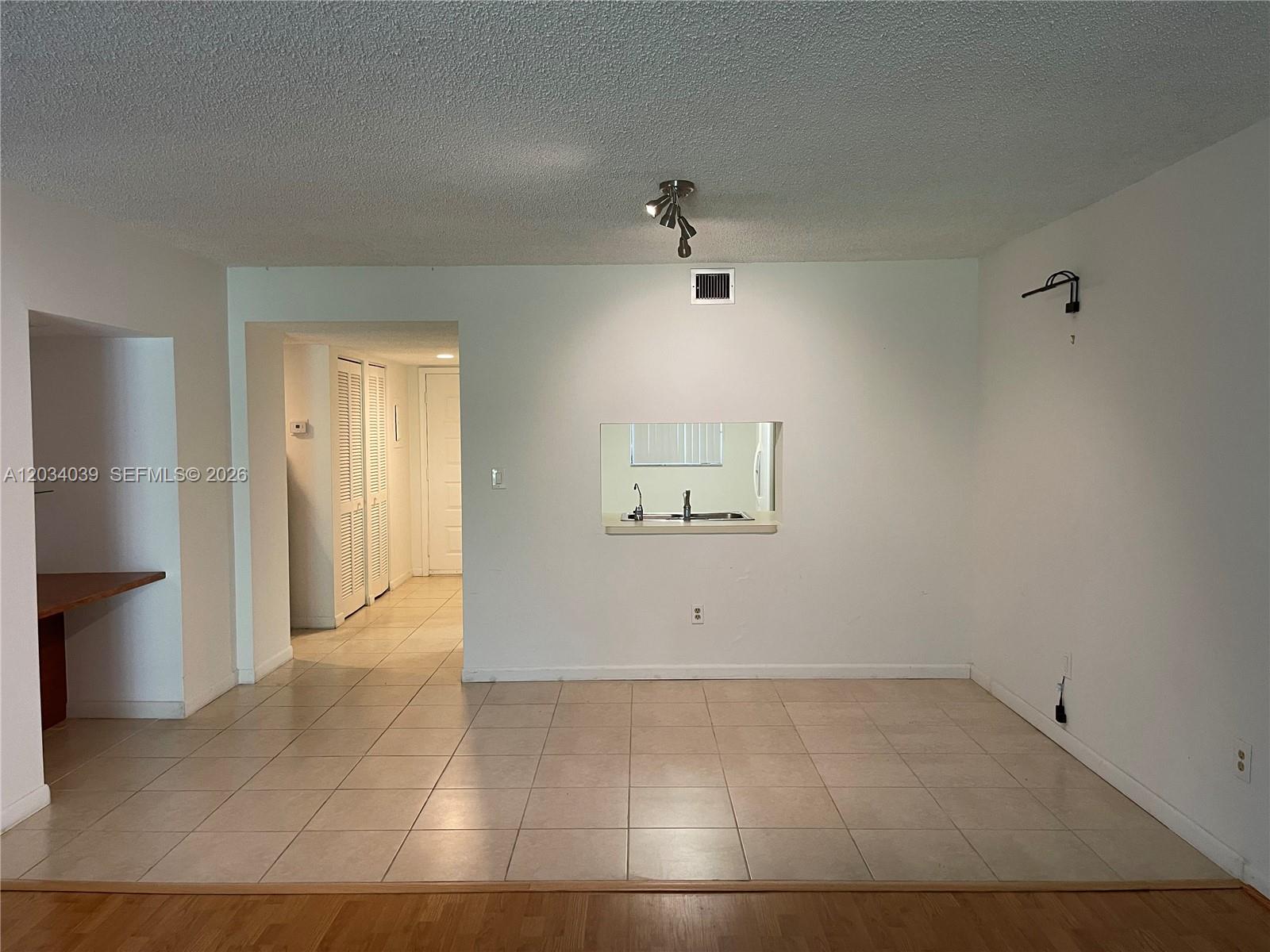 A room with light-colored tile flooring, a kitchen pass-through window, and a ceiling light fixture — 16171 Blatt Blvd # 212, Weston FL 33326, WESTON, FL