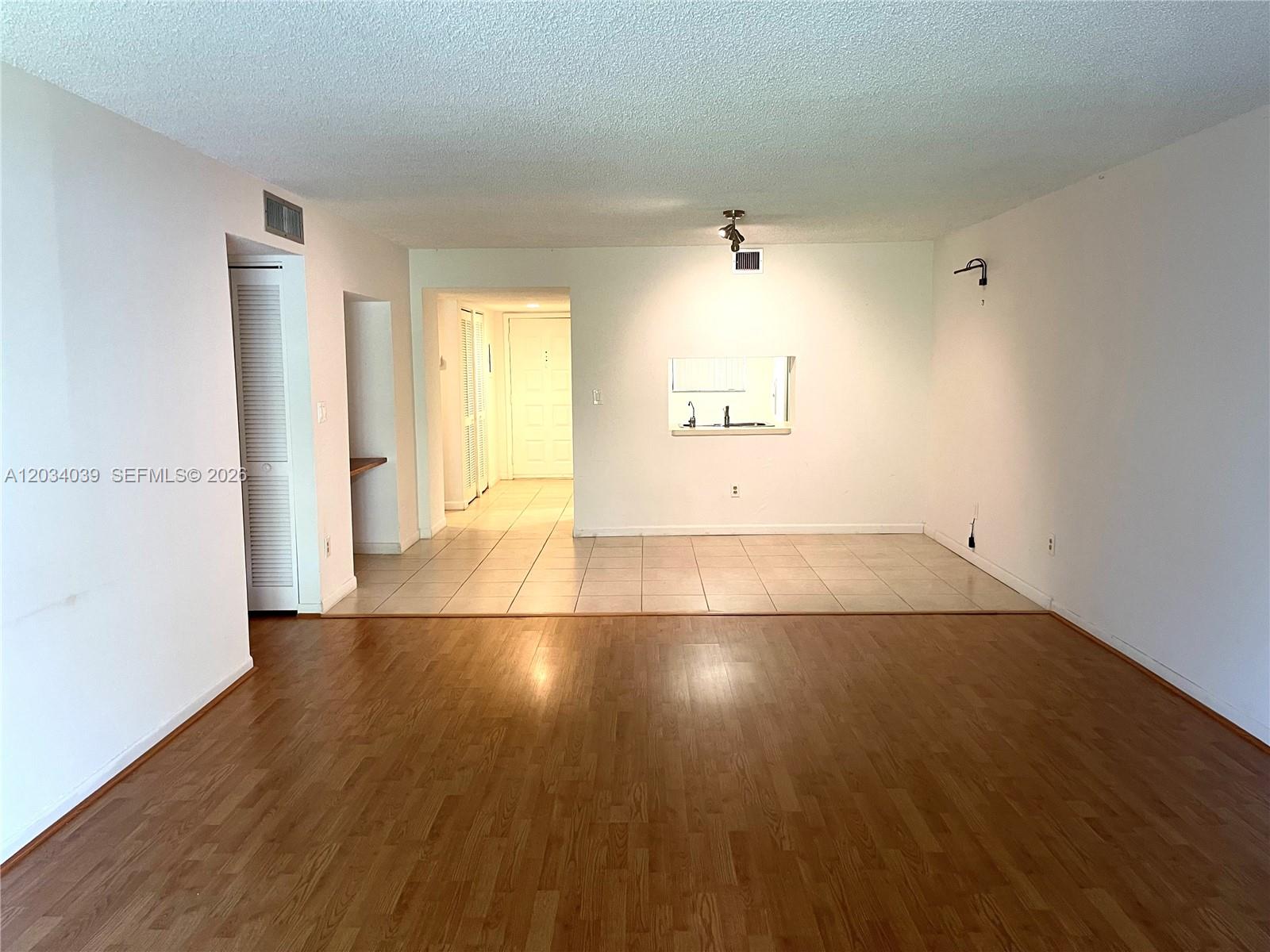 This interior view shows a living area with wood flooring transitioning to a tiled kitchen — 16171 Blatt Blvd # 212, Weston FL 33326, WESTON, FL