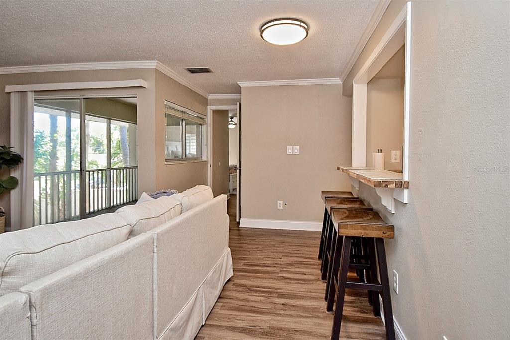 A living room features a sofa, a breakfast bar with stools, and a sliding glass door — 2121 WOOD STREET UNIT 201, SARASOTA, FL