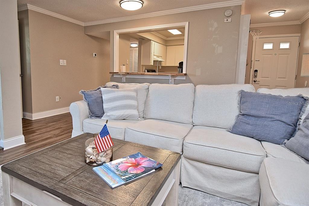 A living room features a white sectional sofa, a wooden coffee table, and a kitchen pass-through — 2121 WOOD STREET UNIT 201, SARASOTA, FL