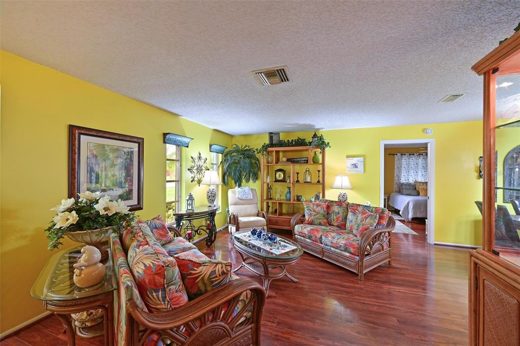 A living room with yellow walls, tropical-patterned furniture, and hardwood floors — 811 ALDERWOOD WAY, SARASOTA, FL