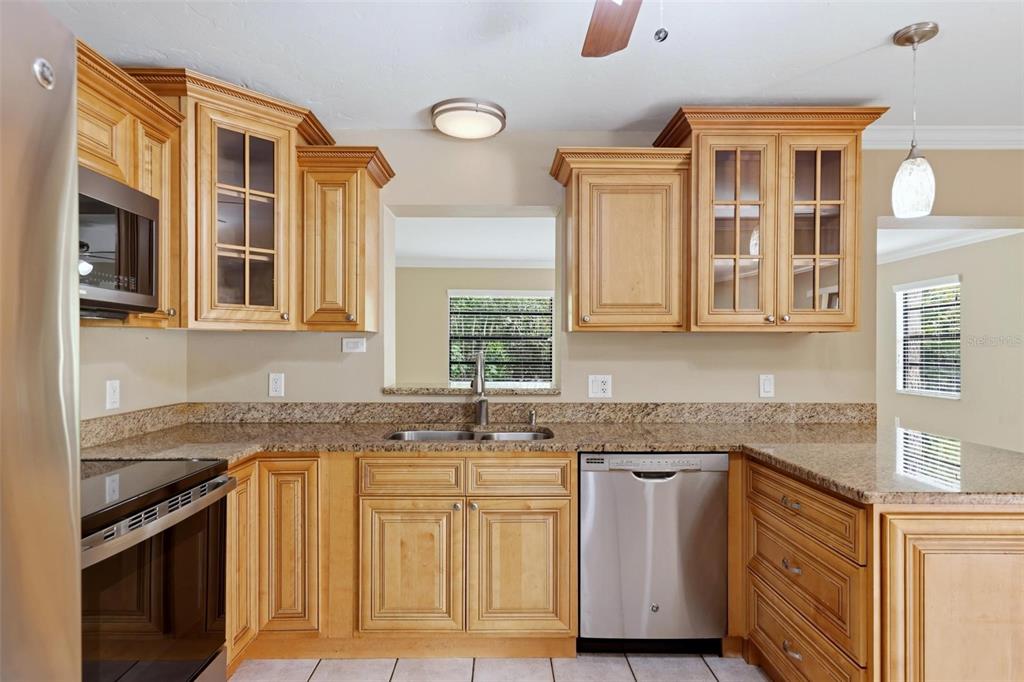 A kitchen features light wood cabinets, granite countertops, stainless steel appliances, and a window view — 3413 51ST AVENUE CIRCLE W UNIT 205, BRADENTON, FL