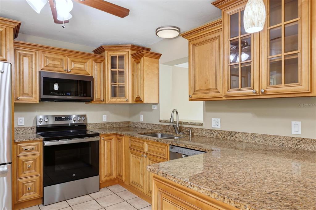 A kitchen featuring light wood cabinets, granite countertops, stainless steel appliances, and tile flooring — 3413 51ST AVENUE CIRCLE W UNIT 205, BRADENTON, FL