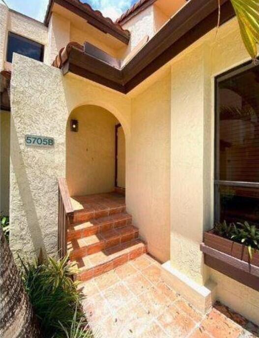 An exterior view of a home entrance with terracotta steps leading to an arched doorway — 5705 Fox Hollow Drive # B, Boca Raton FL 33486, BOCA RATON, FL