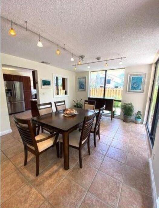 A dining room with a wooden table, chairs, tile flooring, and track lighting — 5705 Fox Hollow Drive # B, Boca Raton FL 33486, BOCA RATON, FL
