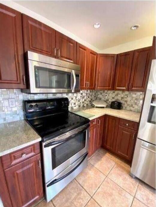 A kitchen with cherry wood cabinets, stainless steel appliances, and a mosaic tile backsplash — 5705 Fox Hollow Drive # B, Boca Raton FL 33486, BOCA RATON, FL