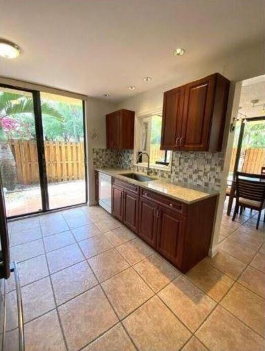 A kitchen with wood cabinets, granite countertops, tile flooring, and a sliding glass door — 5705 Fox Hollow Drive # B, Boca Raton FL 33486, BOCA RATON, FL
