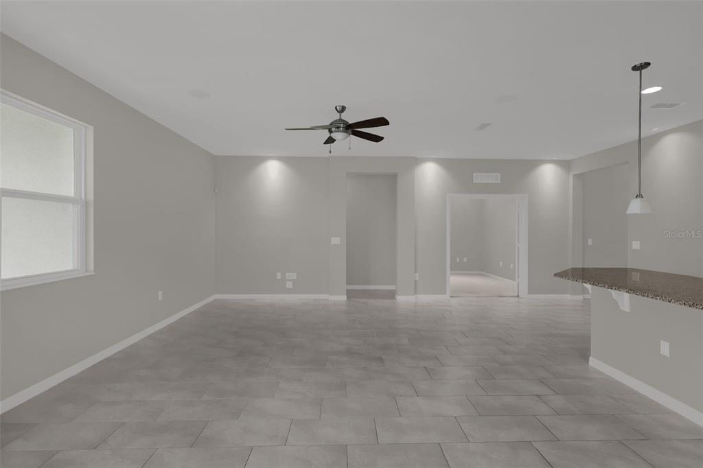 An open-concept living area features light gray walls, large floor tiles, and a ceiling fan — 12112 CARSON DRIVE, ORLANDO, FL