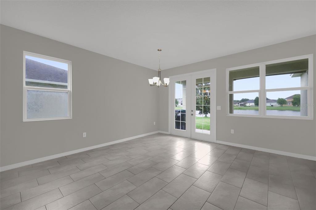 A dining area with gray tile flooring, a chandelier, and glass doors overlooking a pond — 12112 CARSON DRIVE, ORLANDO, FL