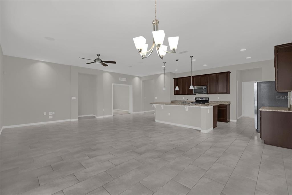 An open-concept kitchen and living area features tile flooring, dark cabinetry, and a central island — 12112 CARSON DRIVE, ORLANDO, FL