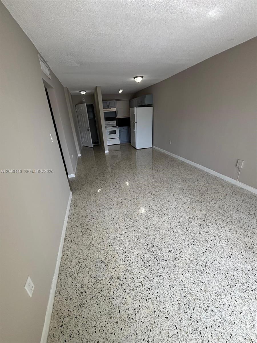 A kitchen with white appliances and grey cabinets opens into a room with terrazzo flooring — 1047 SW 7th St # 12, Miami FL 33130, MIAMI, FL