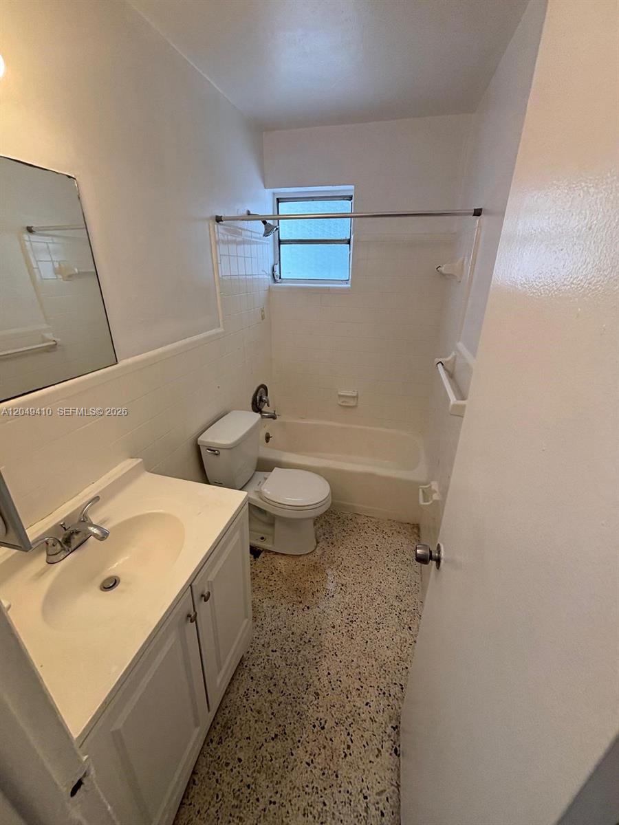 A small bathroom features a white vanity, a toilet, and a bathtub with tile walls — 1047 SW 7th St # 12, Miami FL 33130, MIAMI, FL