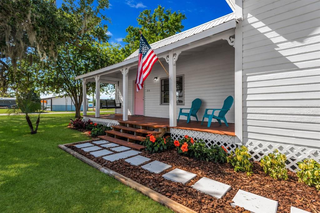 A white house with a front porch, American flag, and a stone walkway — 216 LANGFORD STREET NW, FORT MEADE, FL
