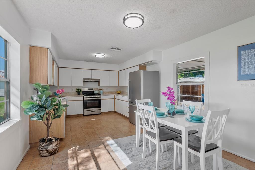 A kitchen and dining area with white cabinets, stainless steel appliances, and tile flooring — 216 LANGFORD STREET NW, FORT MEADE, FL