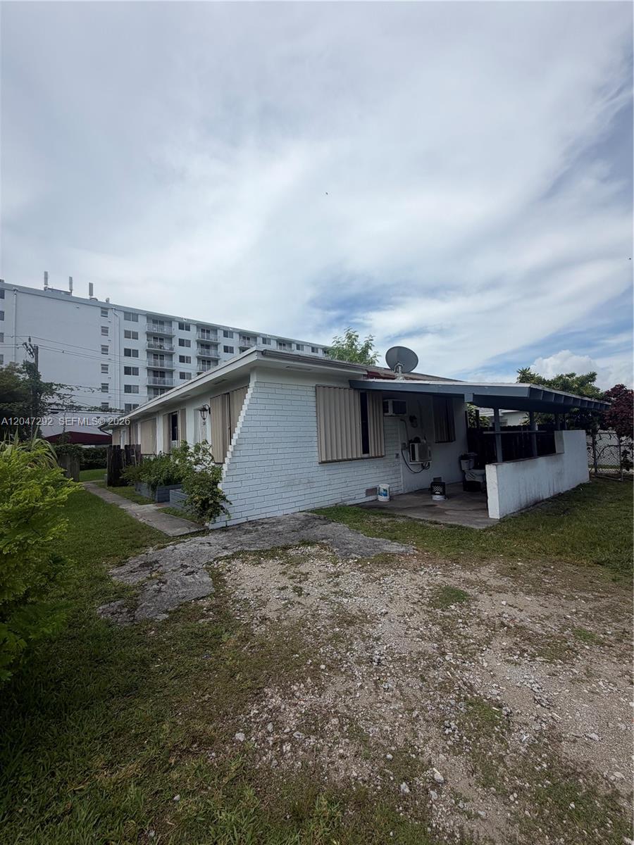 The exterior of a single-story white brick house features a covered patio and gravel driveway — 1258 NE 109th St, Miami FL 33161, MIAMI, FL