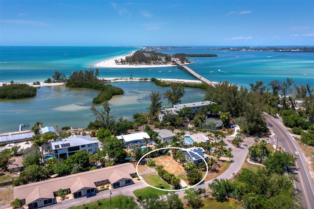 An aerial view shows a vacant residential lot surrounded by tropical vegetation and nearby buildings — 450 FIREHOUSE COURT, LONGBOAT KEY, FL