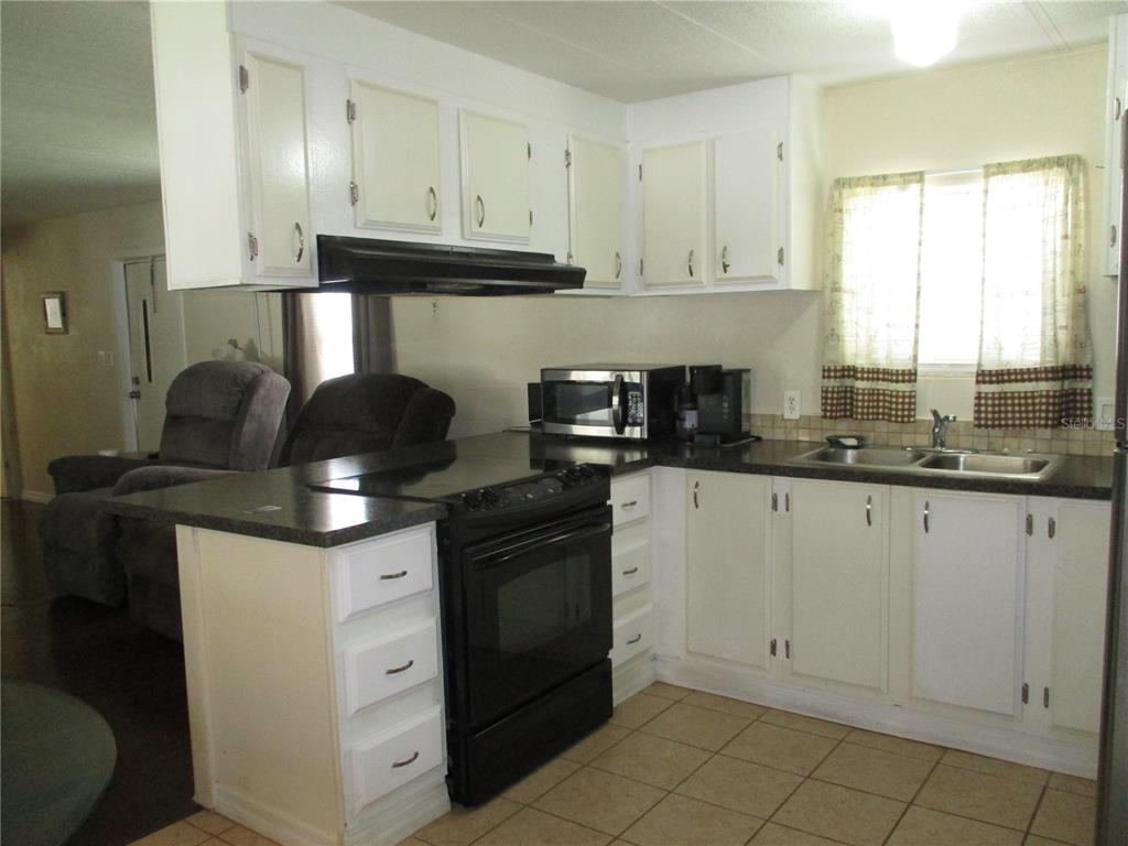 A kitchen with white cabinets, black appliances, and a dark countertop — 92 ROSALIE OAKS BOULEVARD, LAKE WALES, FL