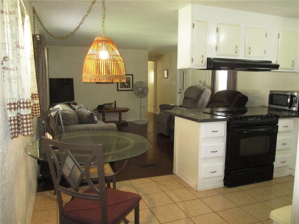 A kitchen with white cabinets and black appliances overlooks a dining area and living room — 92 ROSALIE OAKS BOULEVARD, LAKE WALES, FL